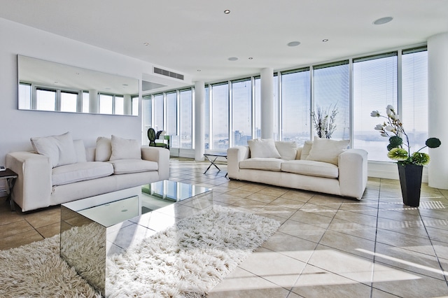spacious bright living room with white couches, white walls, floor to ceiling windows allowing natural light into the room. Sun rooms and floor to ceiling windows
