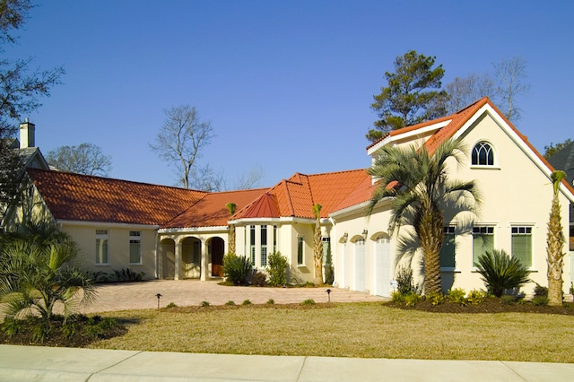 The exterior of a one-story Mediterranean style home with a white stucco exterior and red tile roof.  