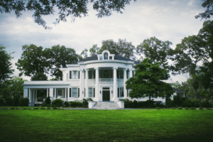 modern, white plantation style home situated on a large expanse of green grass