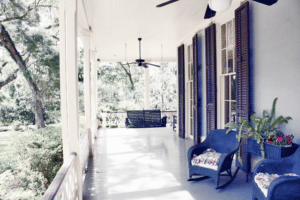 A charming, wrap around porch featuring a swing welcomes folks to sit on a sunny afternoon