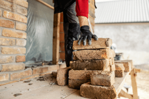 Image of a builder starting to lay bricks after the homeowner learned how to choose a home builder.