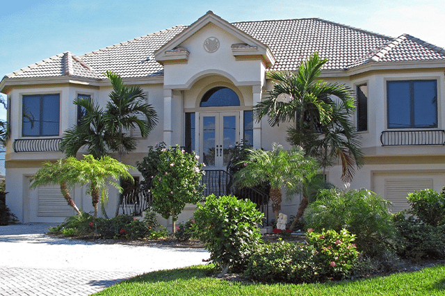 Image of a beautiful coastal Southern home with palm trees and a lush, green yard.